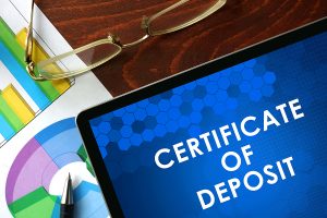 Tablet with certificate of deposit (CD) on a table. Business concept.
