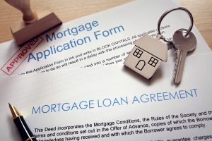 Mortgage loan agreement application with key on house shaped keyring