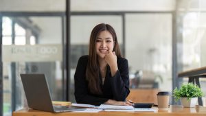 Asian Business woman using calculator and laptop for doing math finance on an office desk, tax, report, accounting, statistics, and analytical research concept